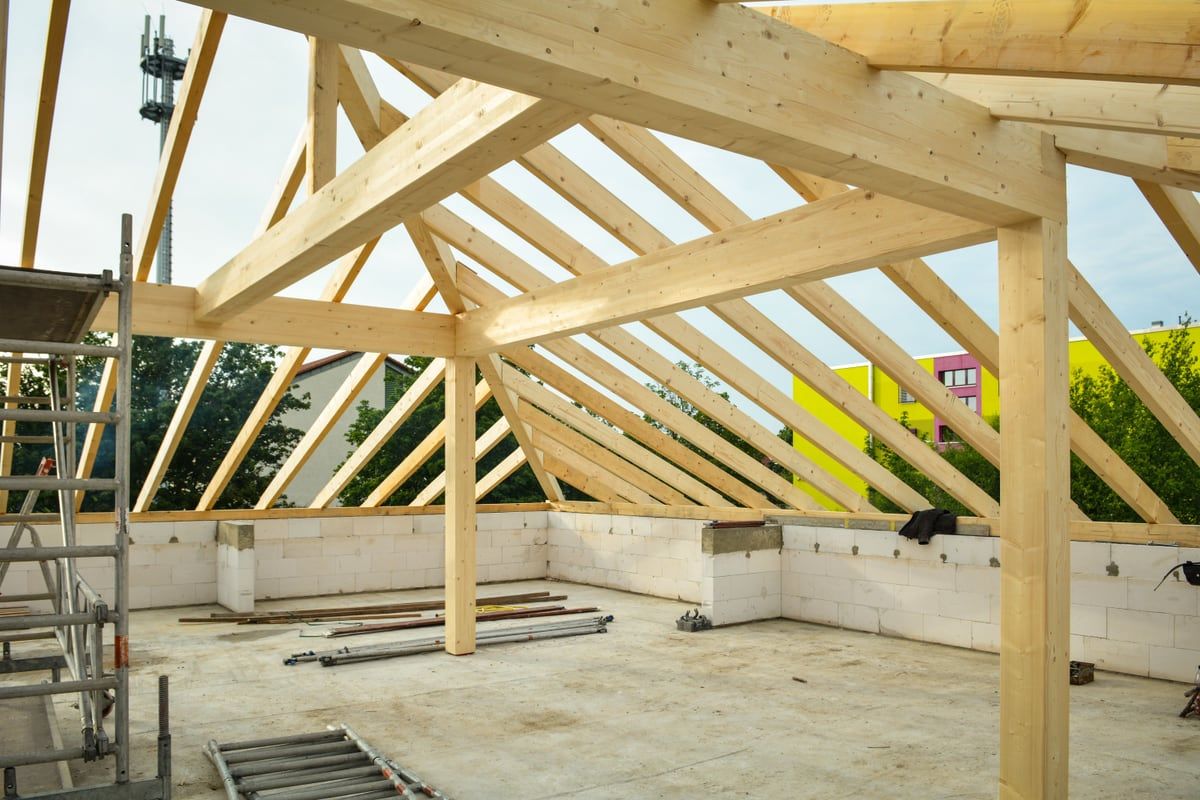 Dachstuhl aus Nadelholz mit Firstpfette, Mittelpfetten und Stützen, aufgelagert auf dem gemauerten Drempel eines Rohbaus